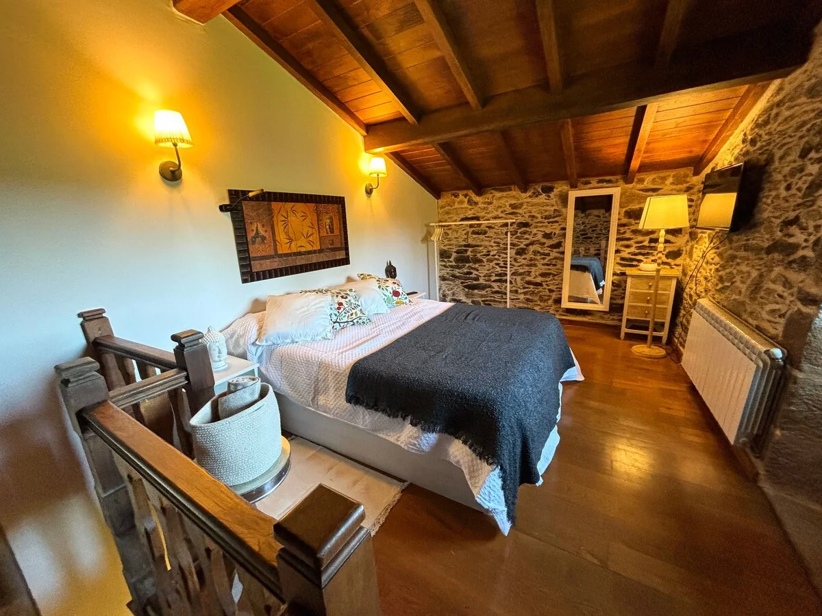 Dormitorio doble con muros de piedra y vigas de madera